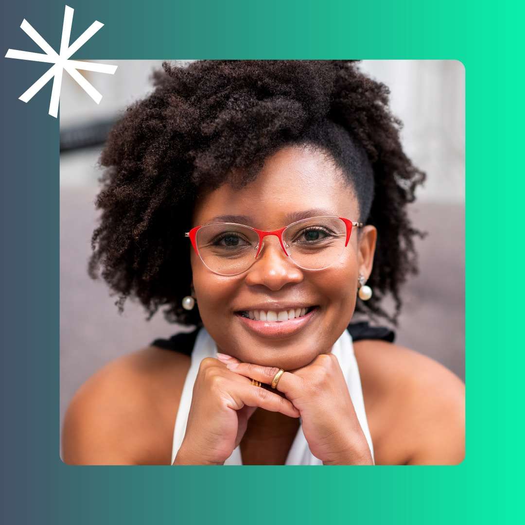 A smiling Black woman with curly hair and red glasses rests her chin on her hands inside a blue and green frame with a white asterisk logo.