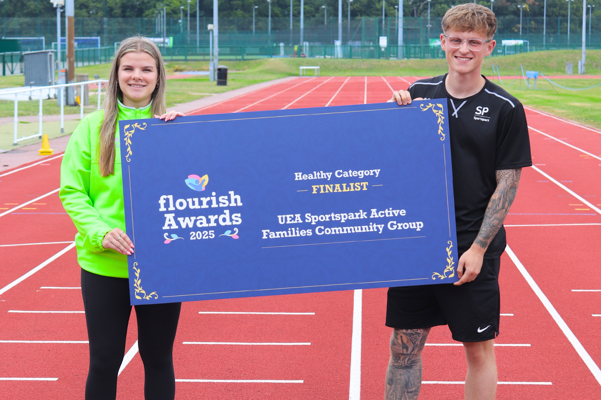two sportspark staff holding sign announcing sportspark as a flourish award finalist