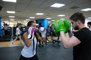 woman in boxing gloves with man in boxing mitts inside gym
