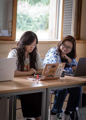 A woman sits at her laptop in a classroom