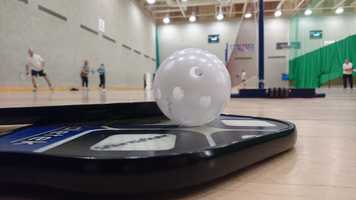 pickleball bat on floor with ball on top