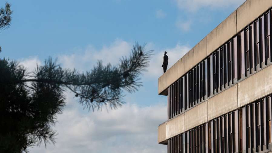 Sir Anthony Gormley's sculptural figure Another Time VIII on top of the UEA building.