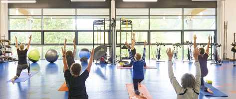 a group of people stretching upwards in a fitness room