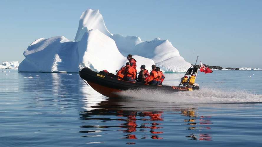 Boat of researchers in front of an iceberg