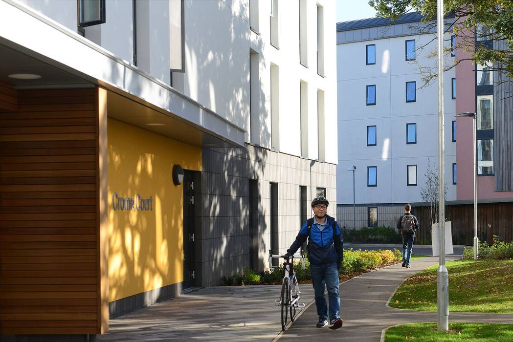 Person walking a bicycle on a path beside Crome Court