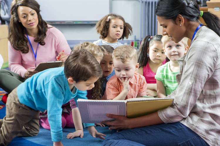 Female teachers storytelling with mixed nursery children