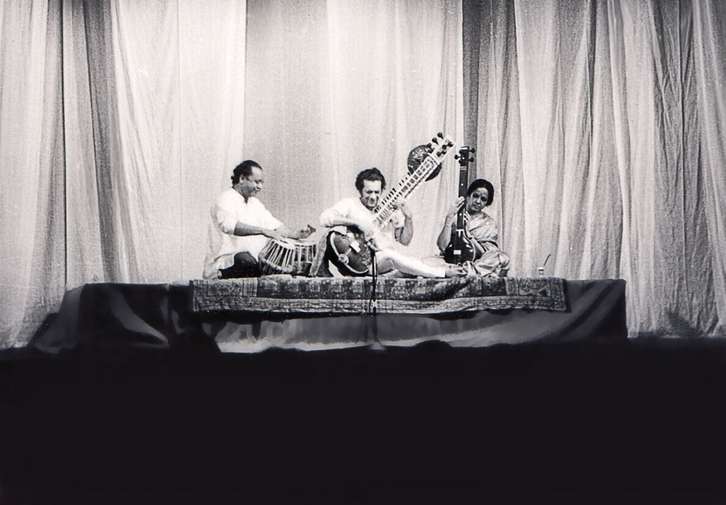 A black and white image of Ravi Shankar taken in 1967 at the LCR. He is flanked by two traditional Indian musicians and he is playing the sitar.