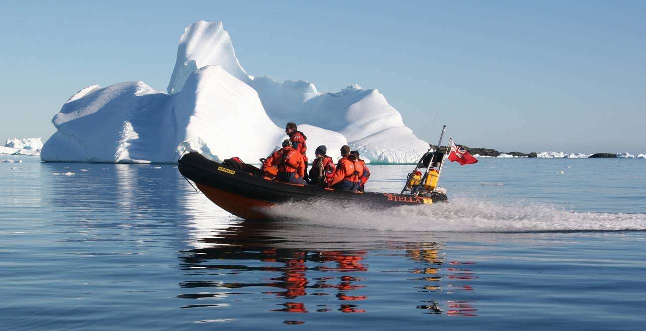 a group of men on a speedboat in front of an iceberg