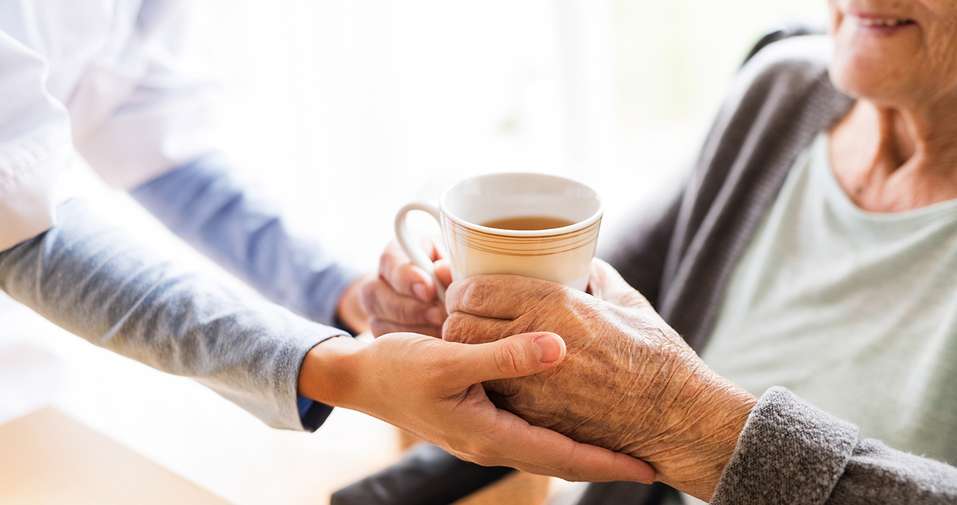 carer-passing-elderly-person-tea