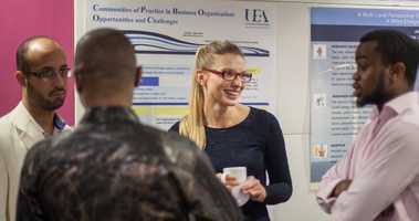four people talking by poster 