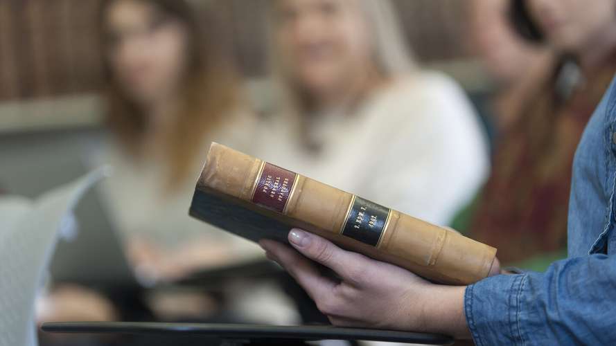 Mature Students in Earlham Hall home to the Law School holding library book
