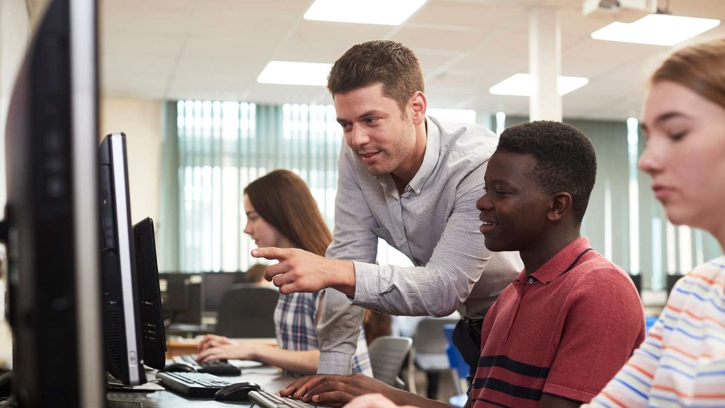 Teacher helping student on computer screen