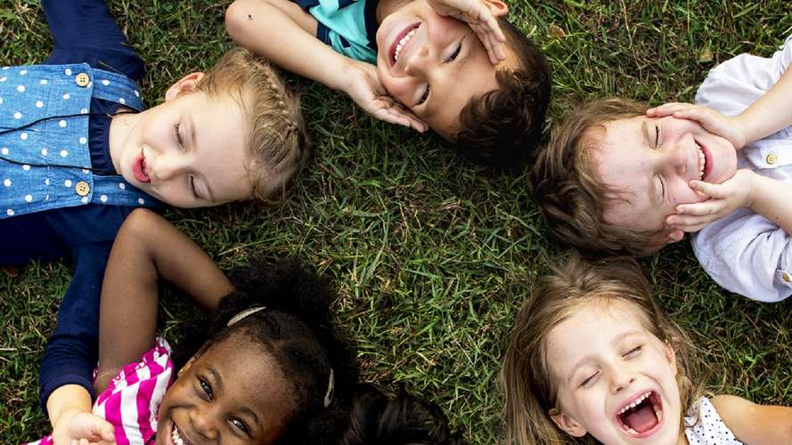 group of young children laying on the grass in a circle