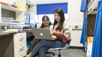 Two students look at laptop screen