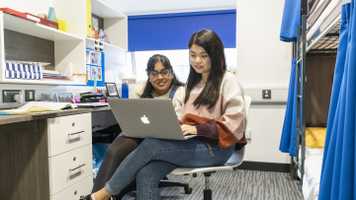 Two students look at laptop screen