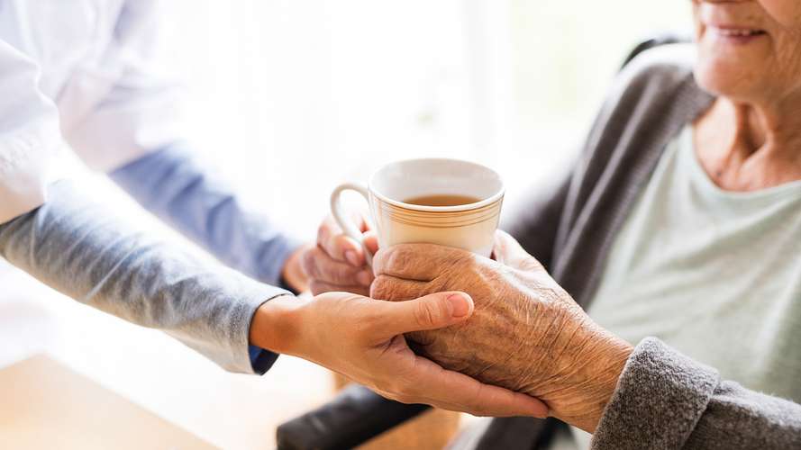 carer handing over cup of tea