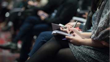 People sat at a conference taking notes