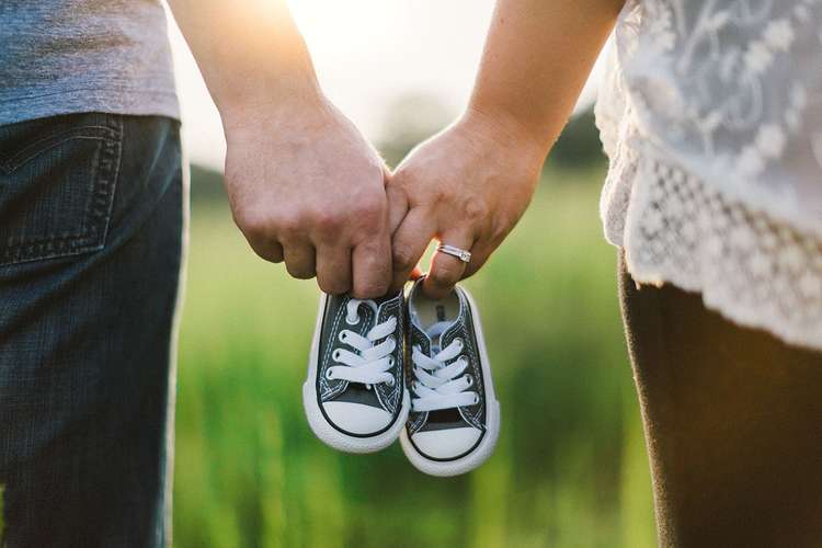 Couple holding baby shoes 