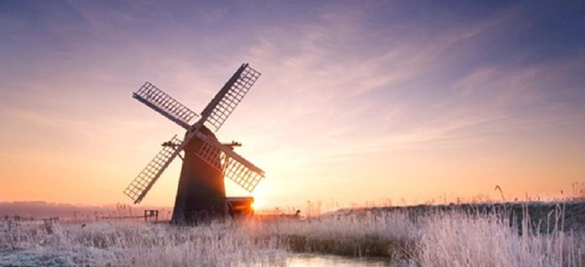 a windmill with snowy grass around it.