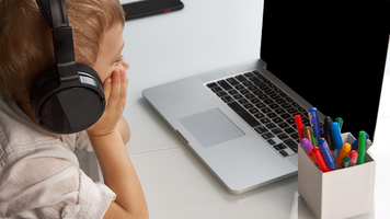 Child wearing headphones sitting in front of a laptop