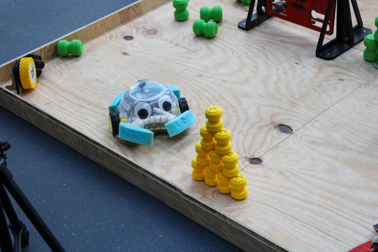 A ScrapBot made of a clear plastic mixing bowl navigates the assault course.