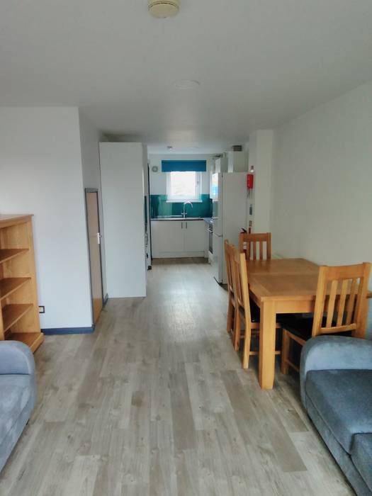 living room features a dining table with chairs, a sofa, a bookshelf, and a view into a kitchen area.