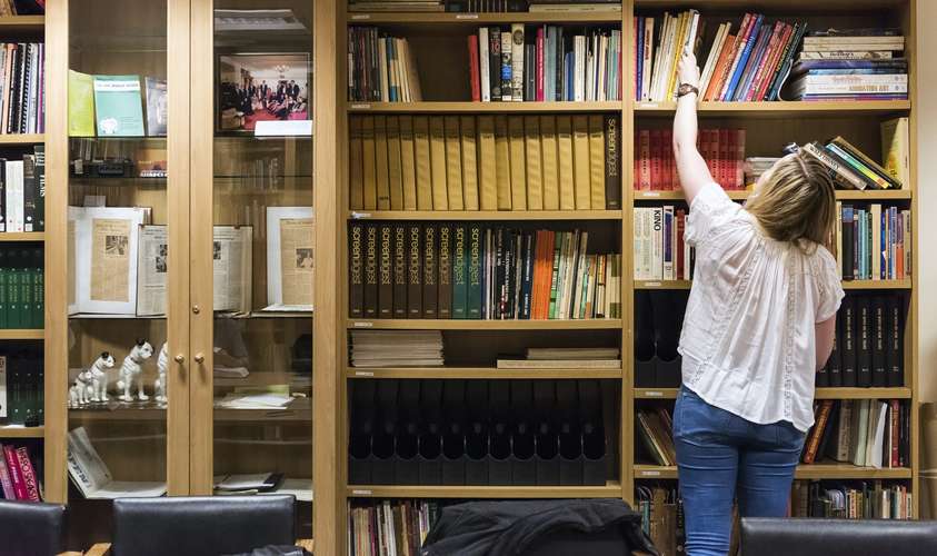 A student reaching for a document at the East Anglian Film Archive