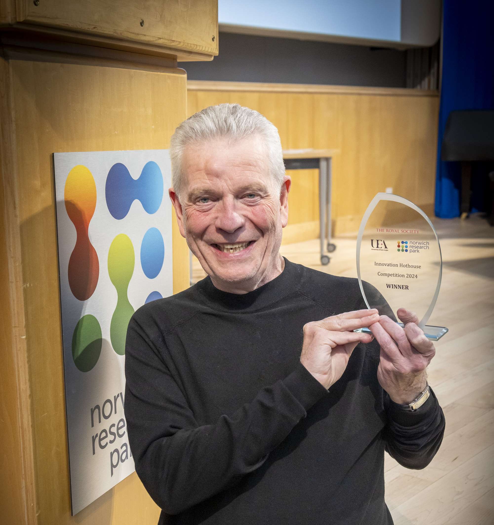 An image of a man smiling at the camera holding an award.