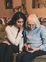 young woman helping older woman with mobile device