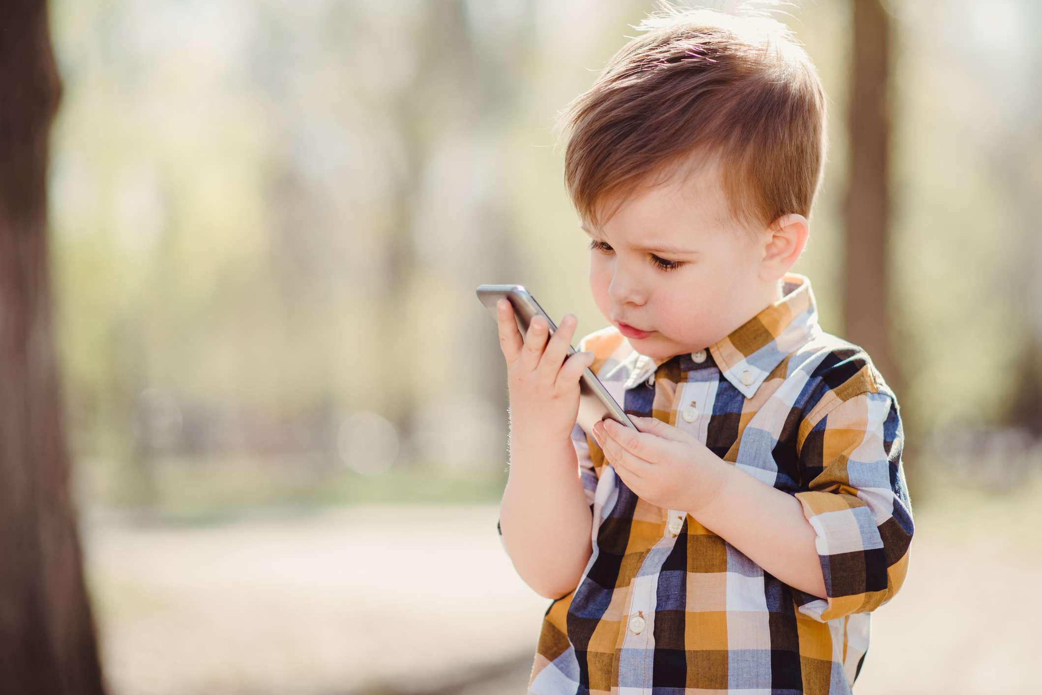 Young boy toddler looking at a mobile phone