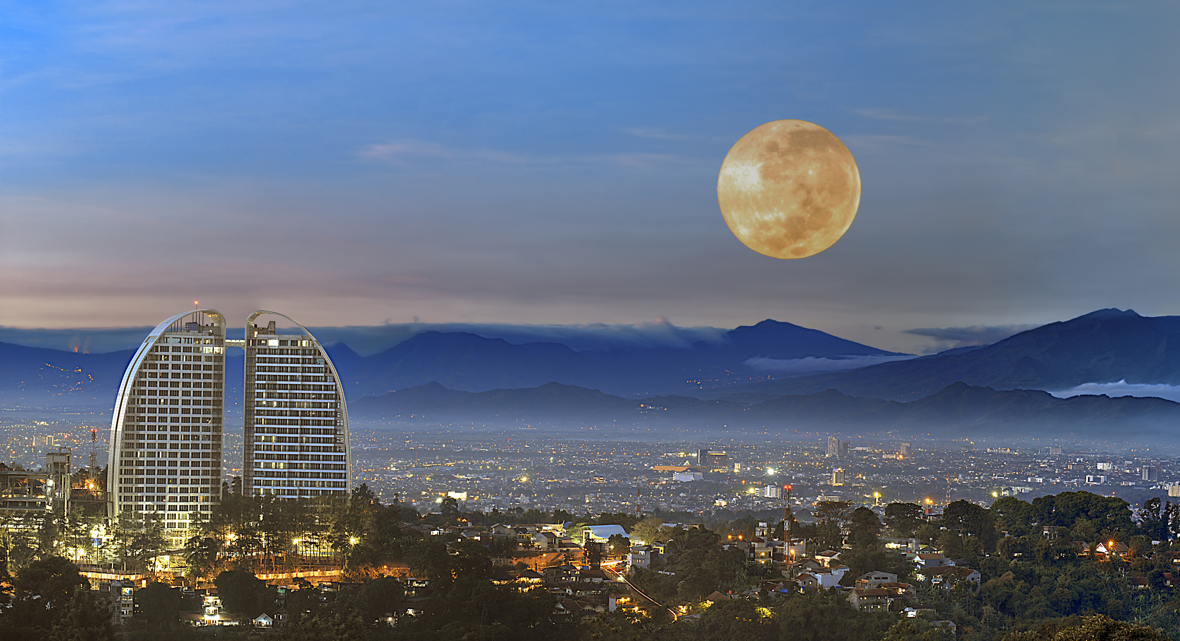 A modern, illuminated city skyline at dusk.