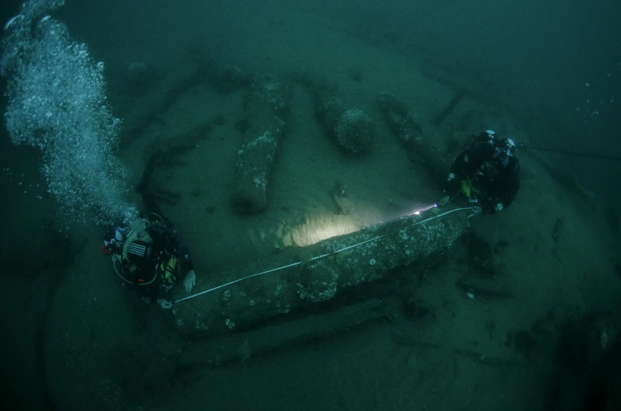 Underwater photograph of two divers measuring a canon