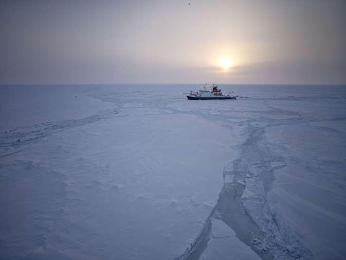 Icebreaker ship in Arctic ice at sunset