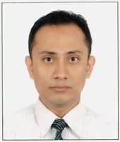 Man with short dark hair wearing a striped shirt and tie, looking directly at the camera against a plain white background.