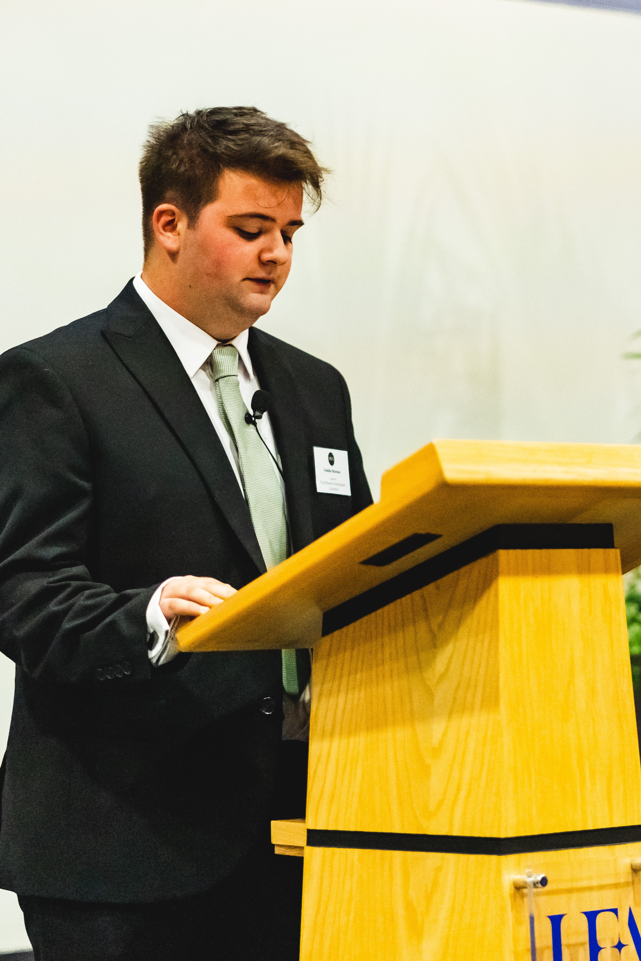 Freddie stands at a podium speaking at UEA's 60th Anniversary Scholarship Reception.