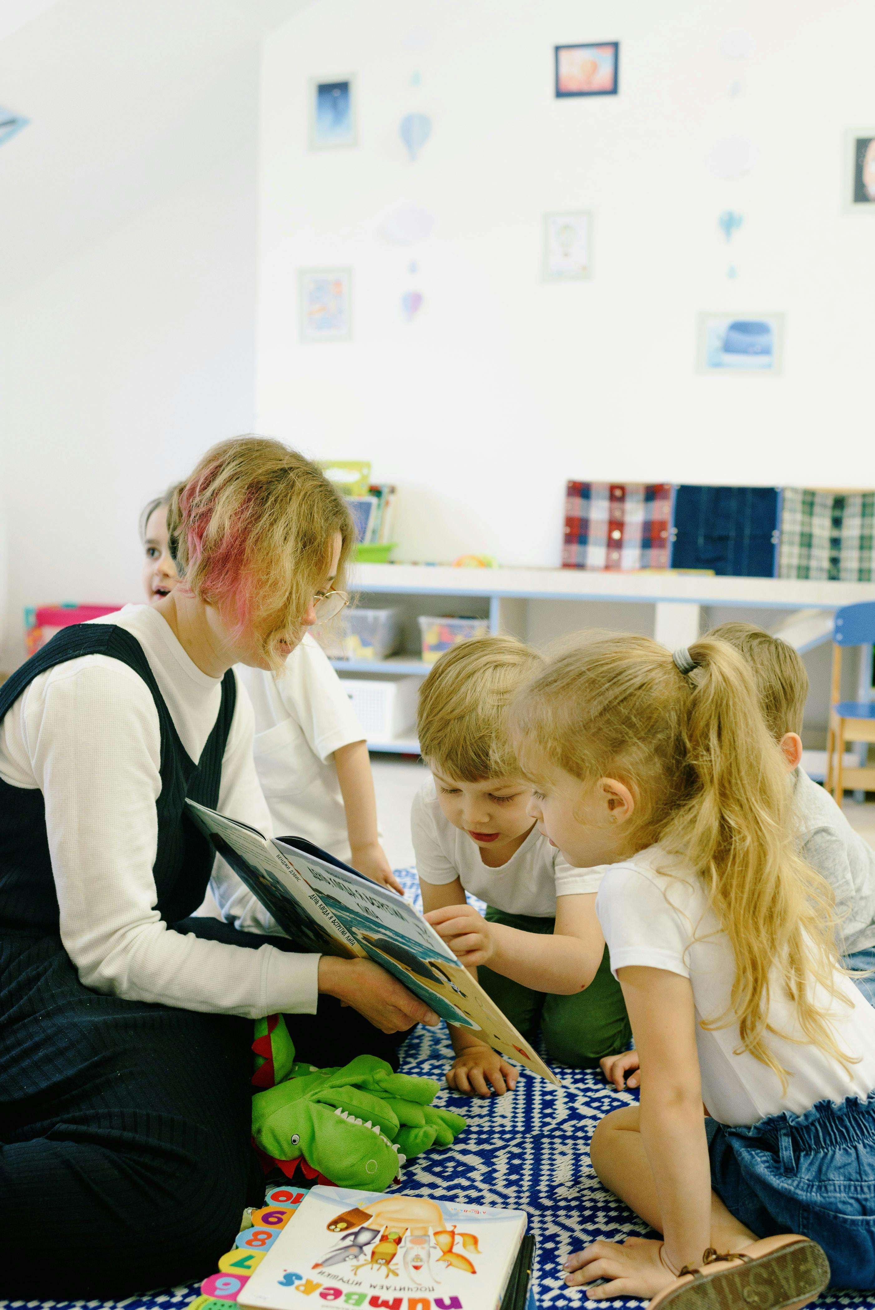 Female teacher showing nursery children a book