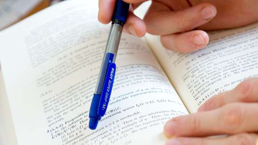 Mathematic student referring to a mathematical book.