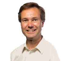 A smiling man with short brown hair wearing a white collared shirt against a plain white background.