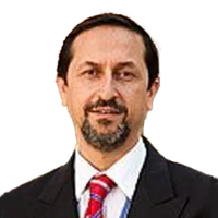 Man in a suit with a red striped tie, short dark hair, and a goatee, smiling slightly against a plain white background.