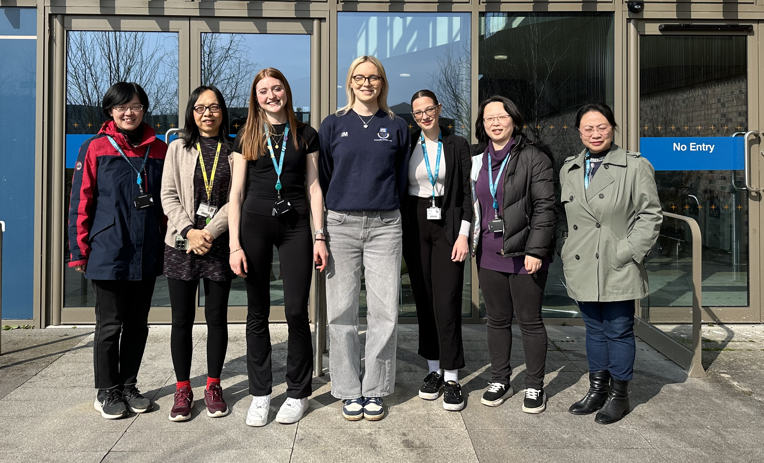 Seven people standing outside the Bob Champion Research and Education building