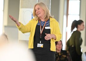 A member of staff smiling and speaking to an audience. 