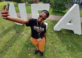 Student taking picture with UEA sign