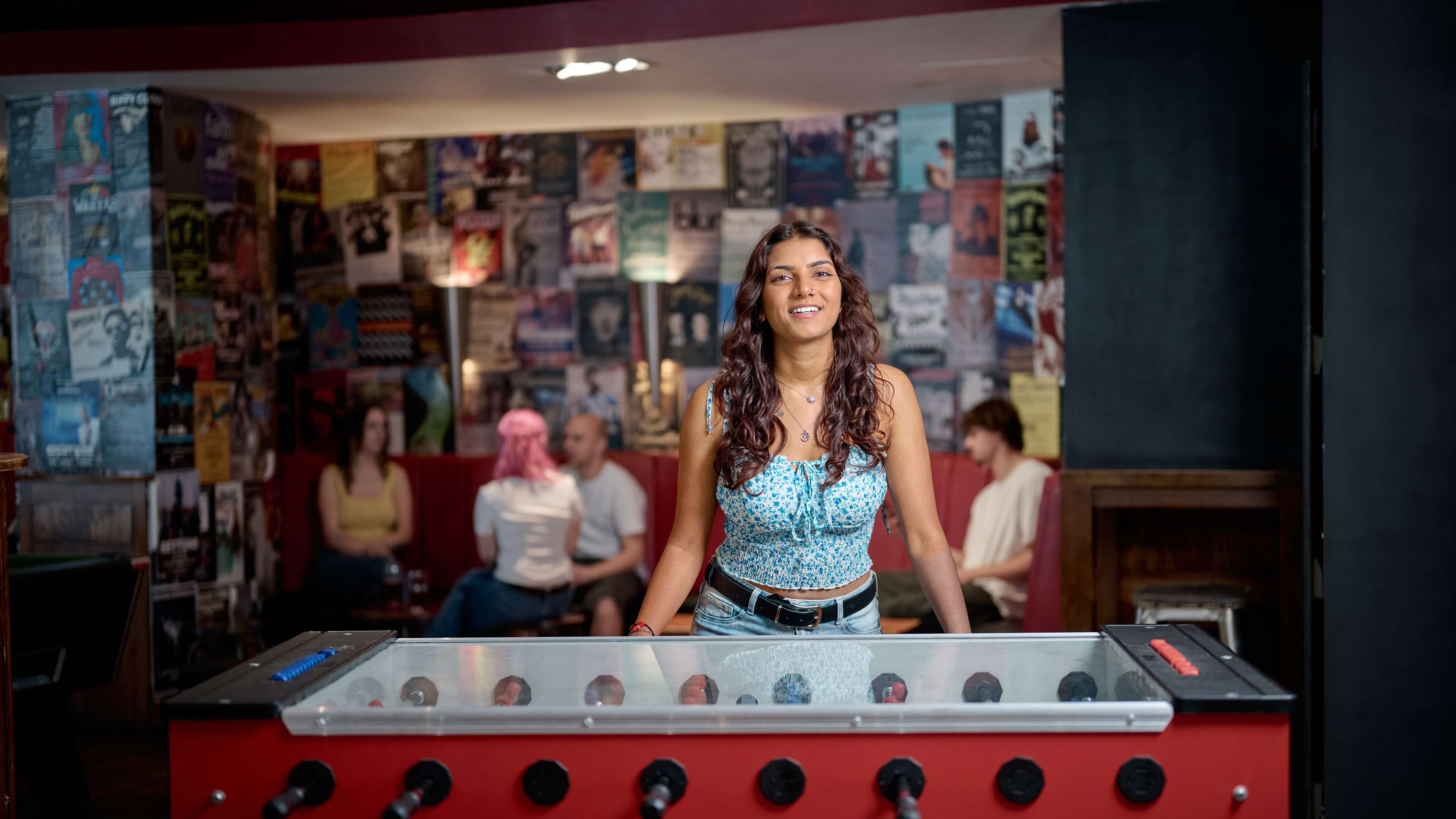 A student plays foosball and smiles at the camera.