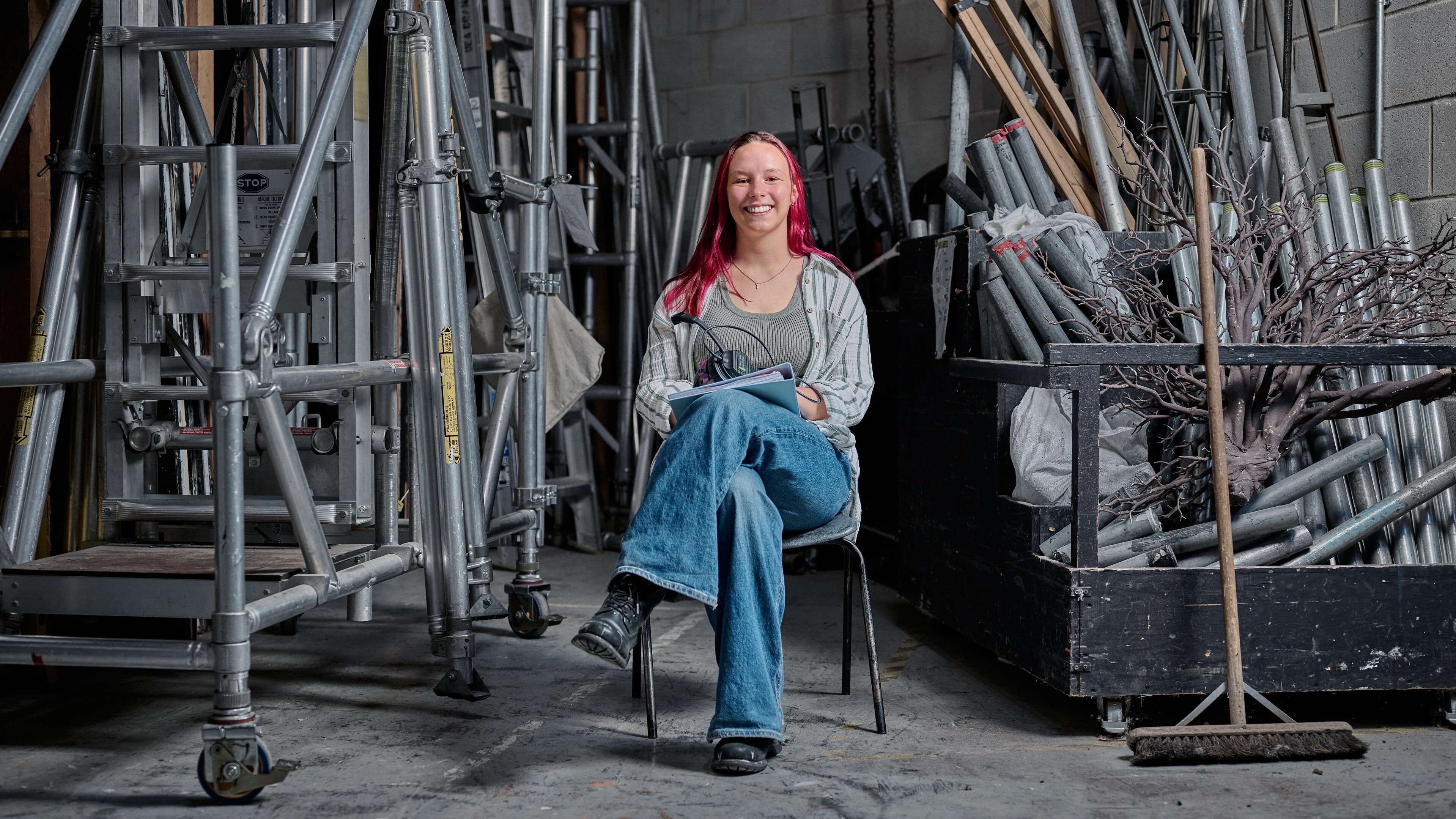 A student sits surrounded by theatre equipment.