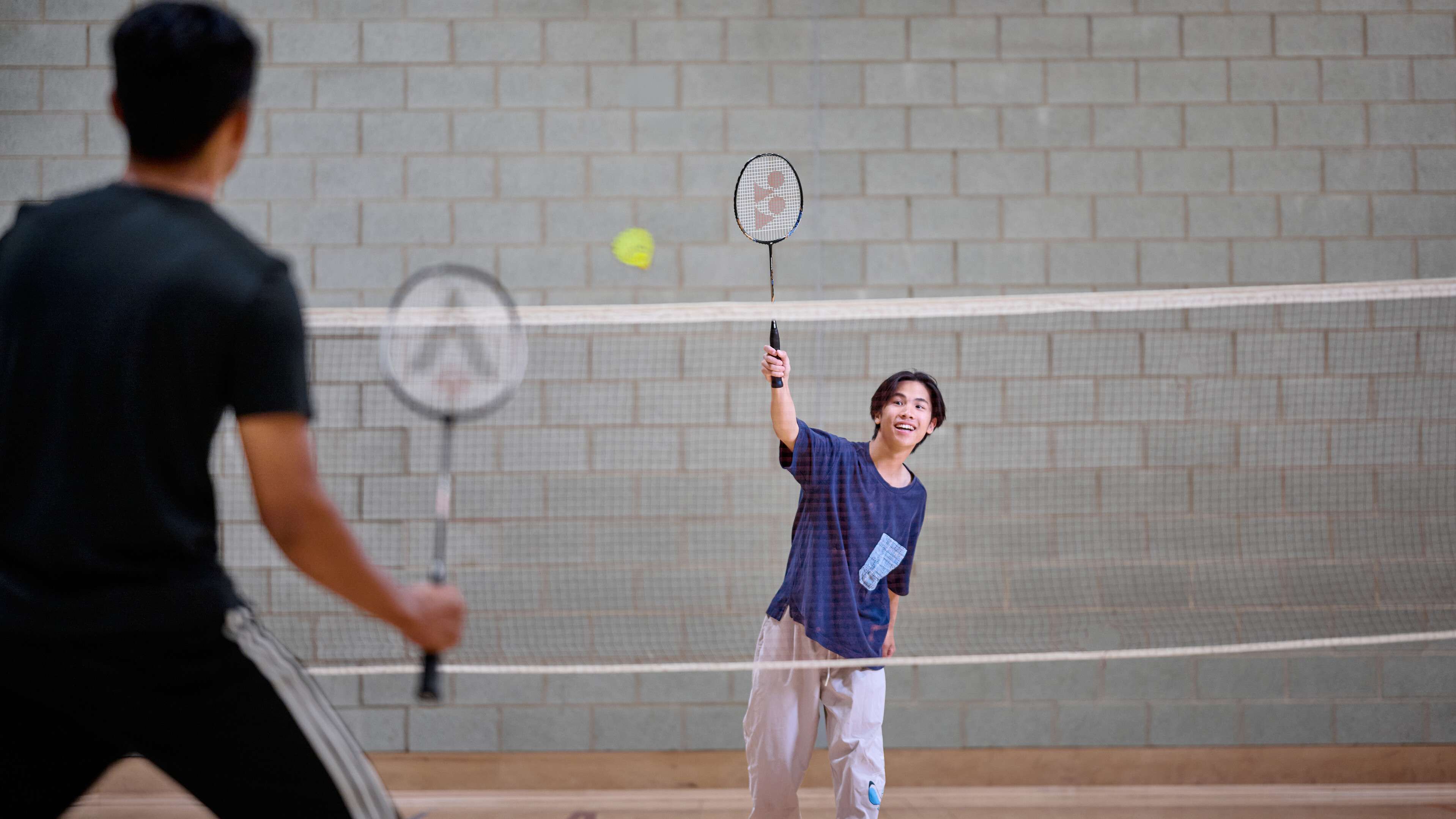 Two students play badminton.
