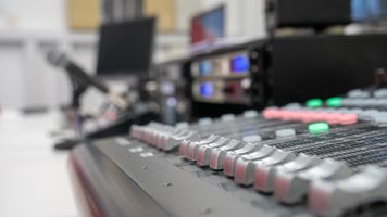 Up close shot of the faders on the vision mixing desk in the control room of Broadcast House.