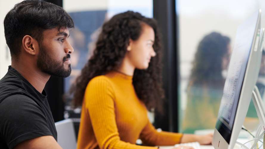 Mature students working on computers in media suite.