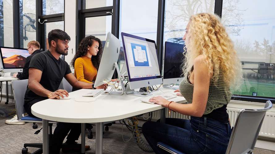 Mature students working on computers in media suite.