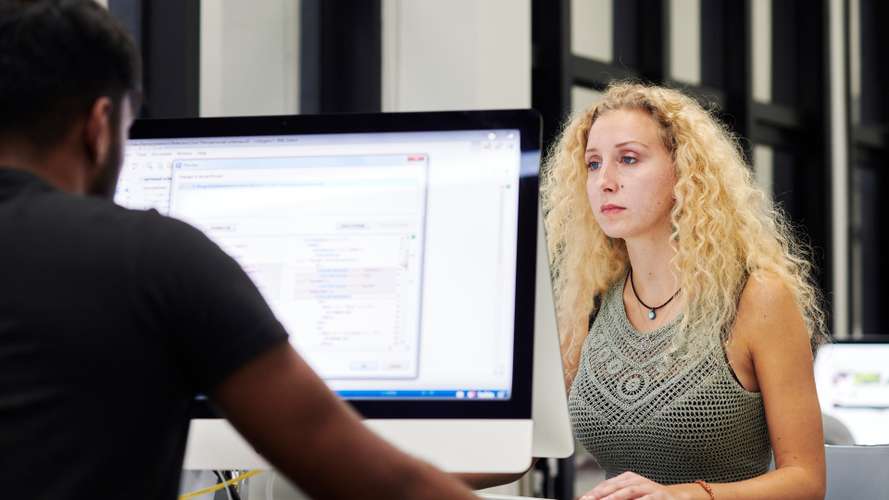 Mature students working on computers in media suite.