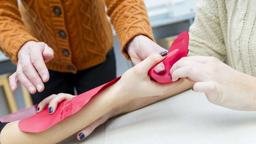 Students learning therapy techniques using an arm